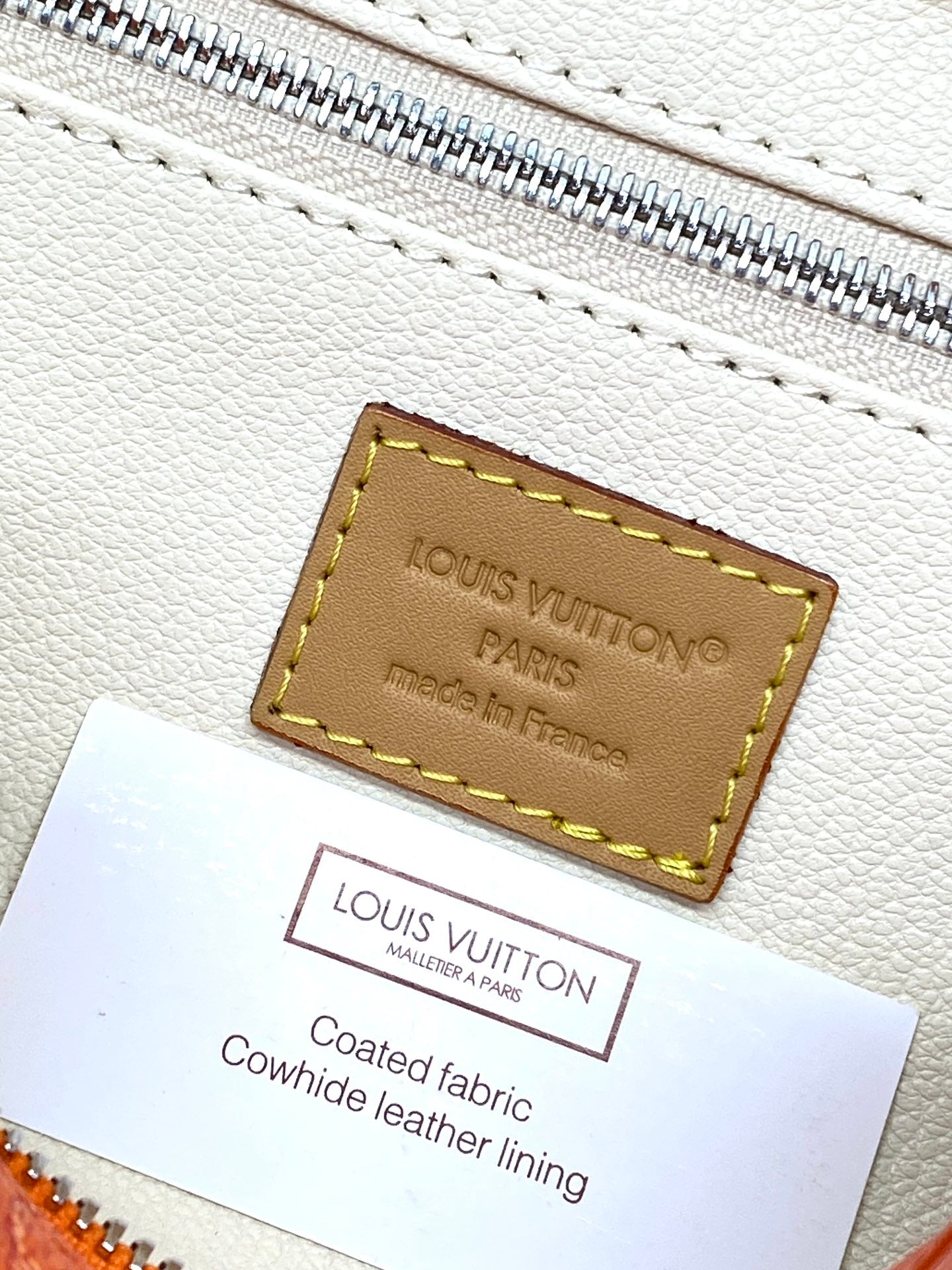 Beige interior fabric label with 'Louis Vuitton' and 'Coated fabric lining' text