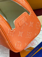 Orange monogram toiletry bag corner close-up with stitched leather and silver zipper
