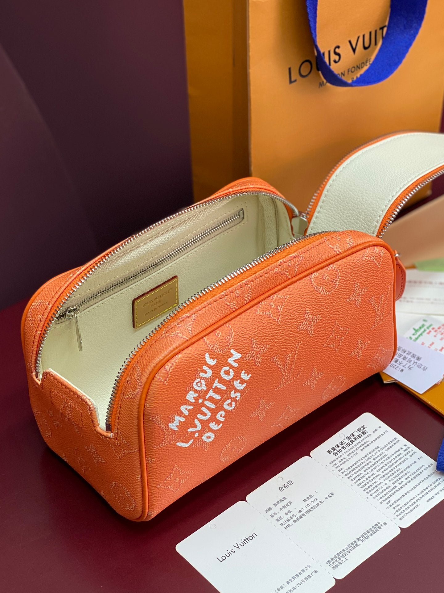 Orange monogram toiletry bag open to reveal beige lining and front zip pocket