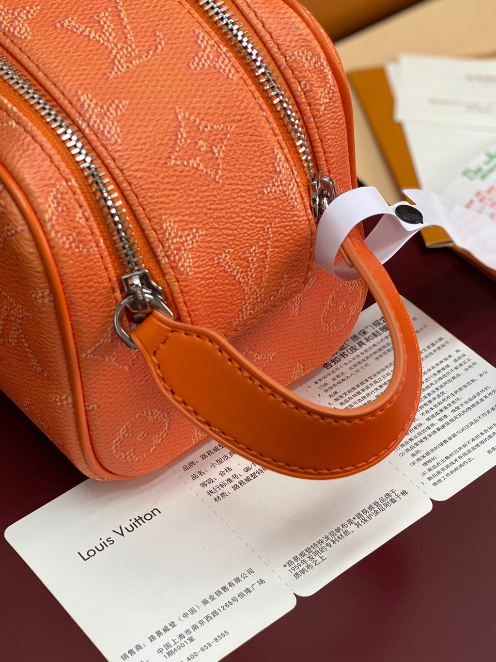 Orange monogram toiletry bag with leather strap loop and silver zipper hardware