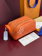 Orange monogram toiletry bag with top zipper and wrist strap, gold hardware