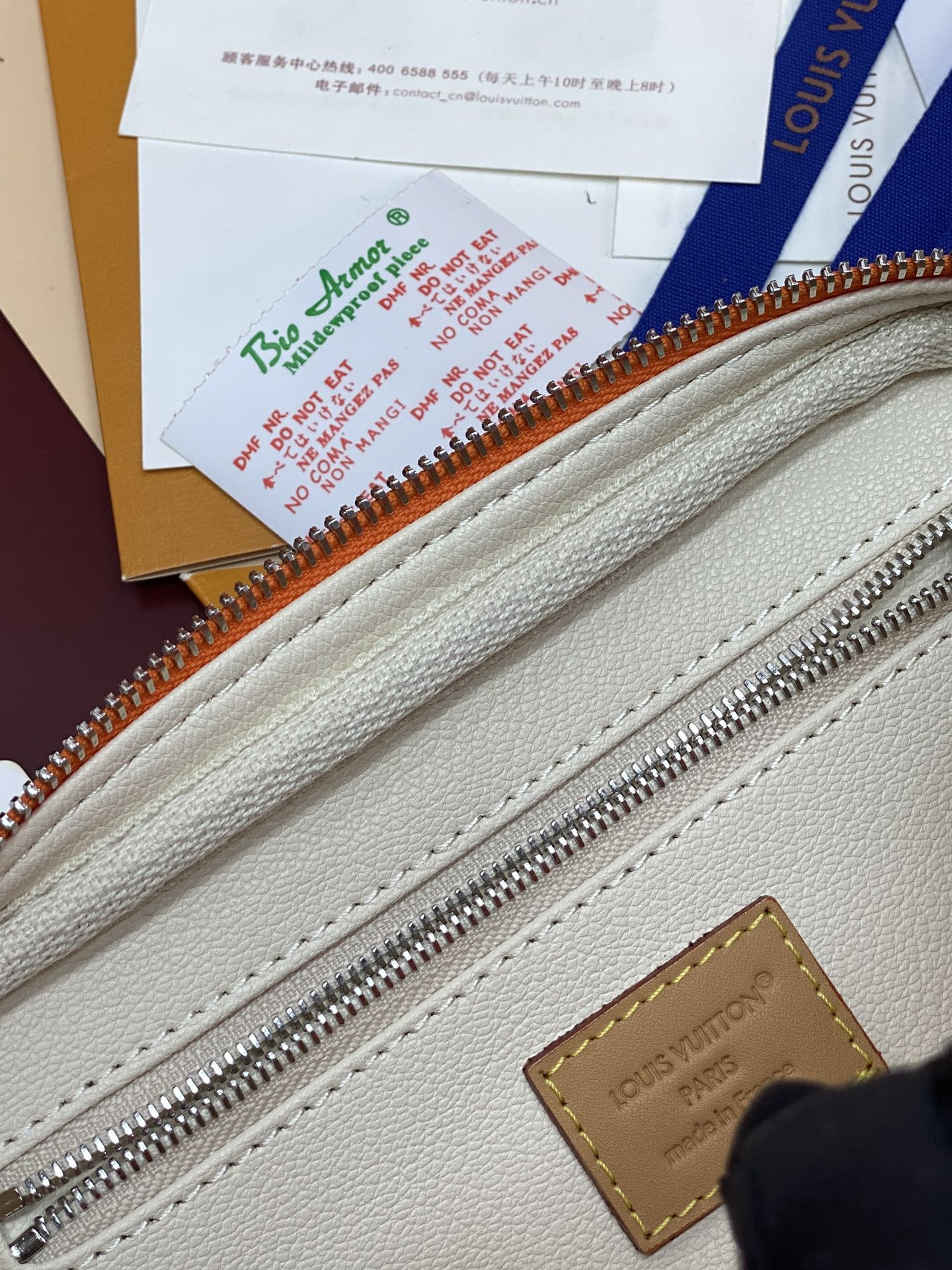 Light beige fabric lining with silver zipper teeth and stitched leather edge