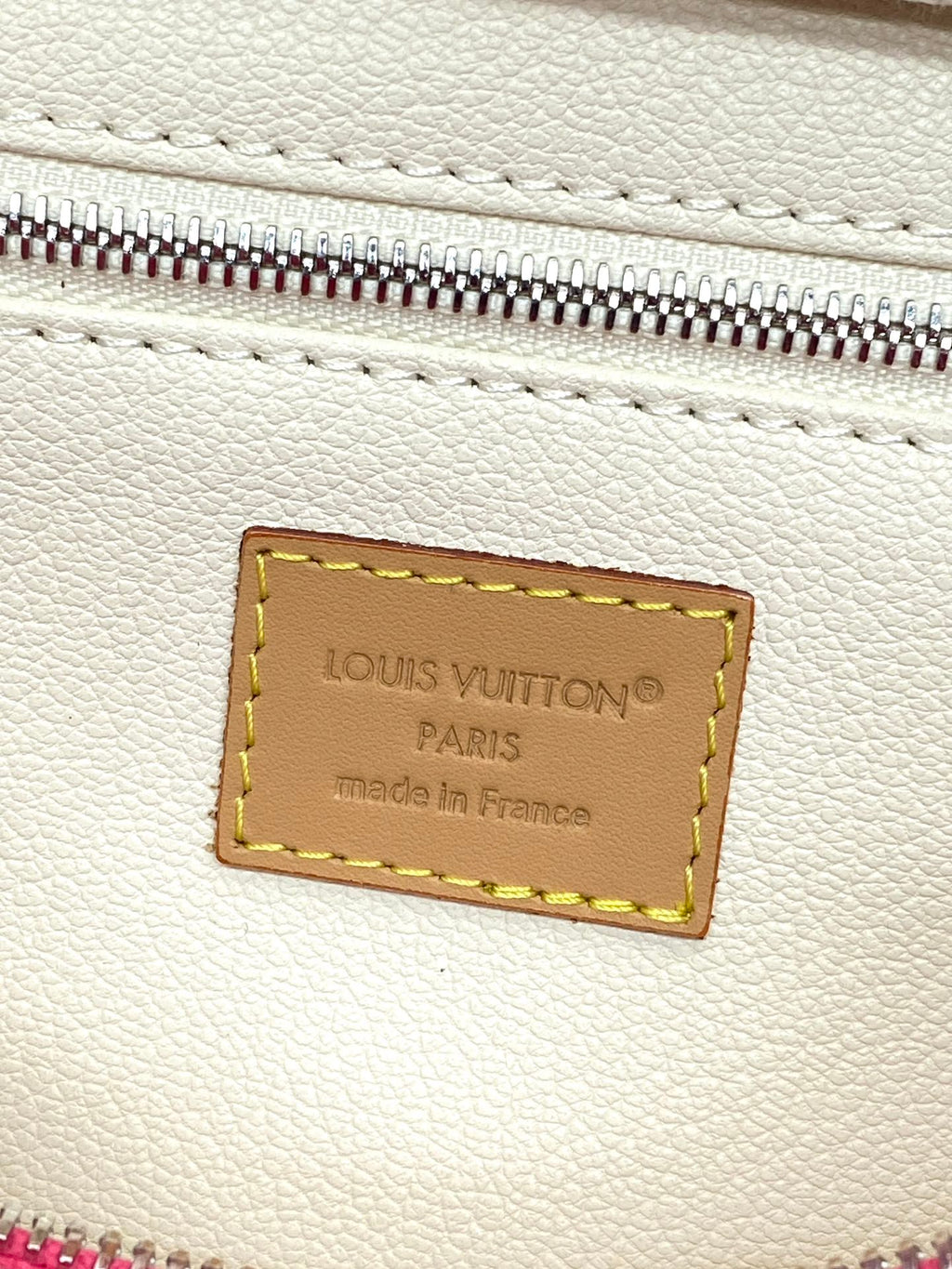 White leather interior panel with Louis Vuitton logo patch and silver zipper