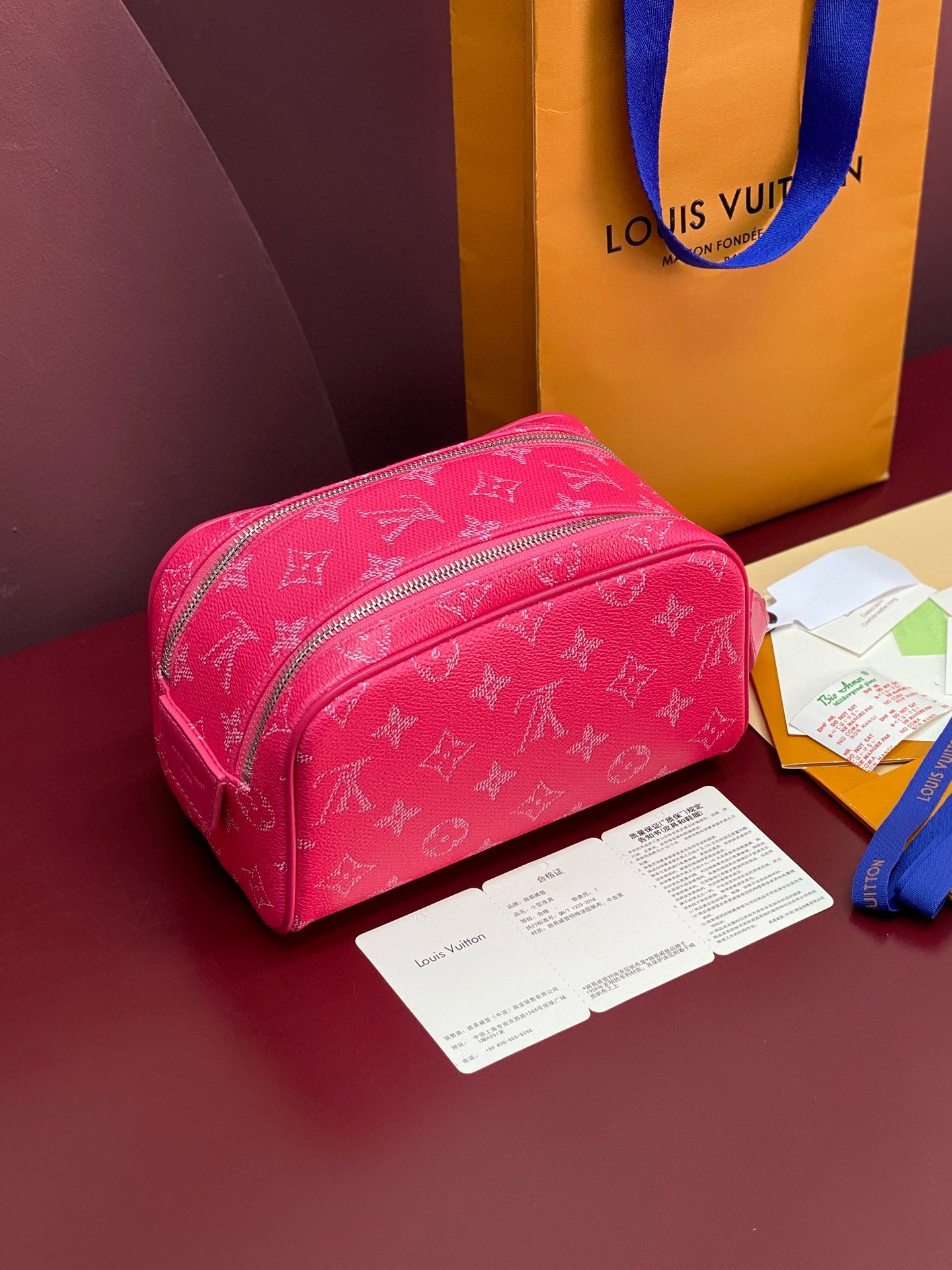 Pink monogram toiletry bag, angled view, front zip pocket and strap