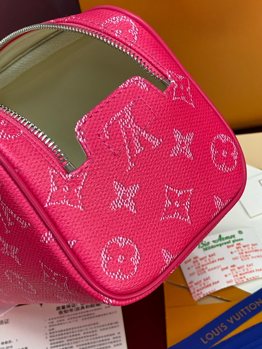 Pink monogram toiletry bag open with interior pocket and zipper trim