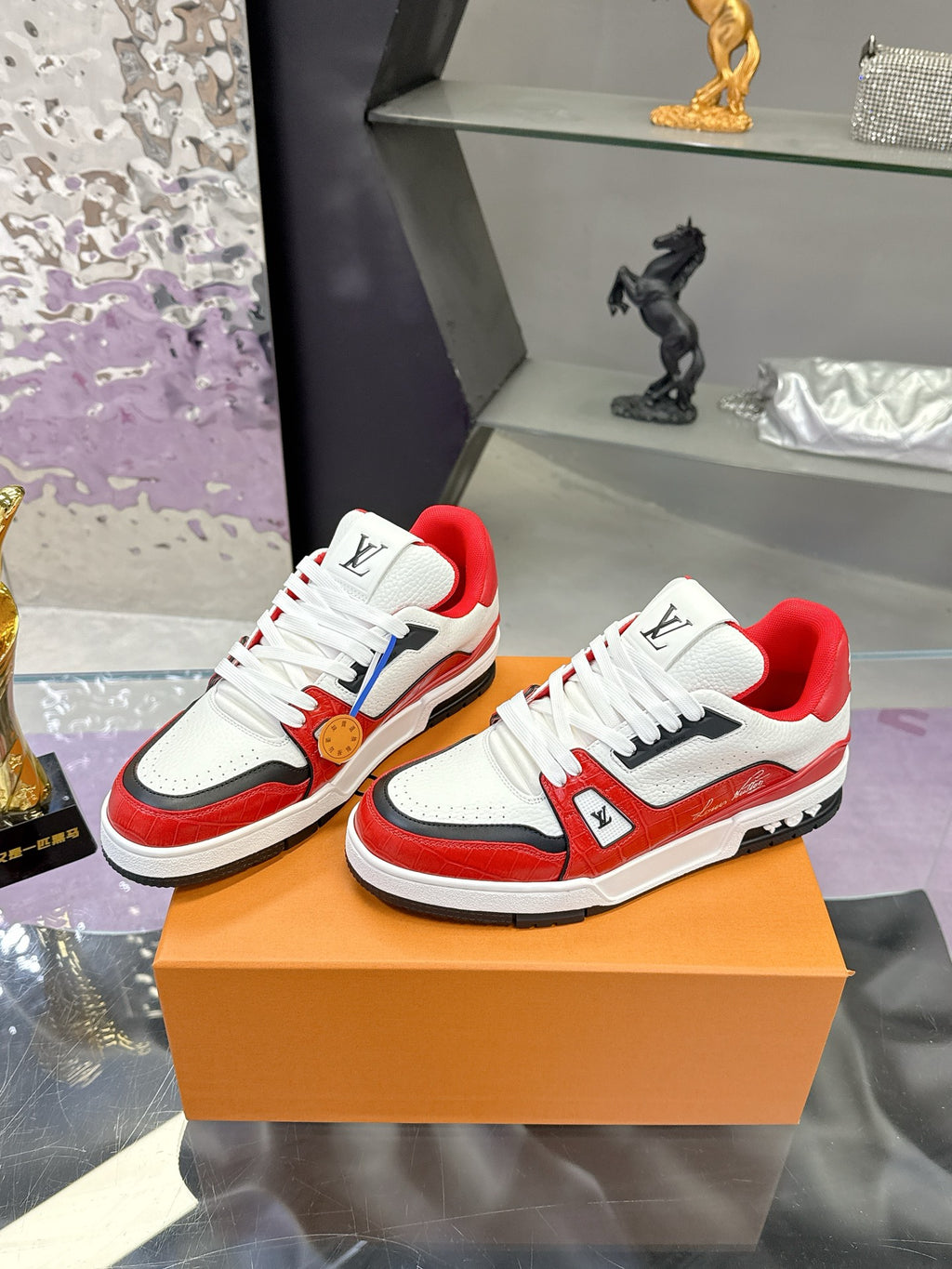 Pair of white and red Louis Vuitton low-top sneakers on display, lace-up with LV patches