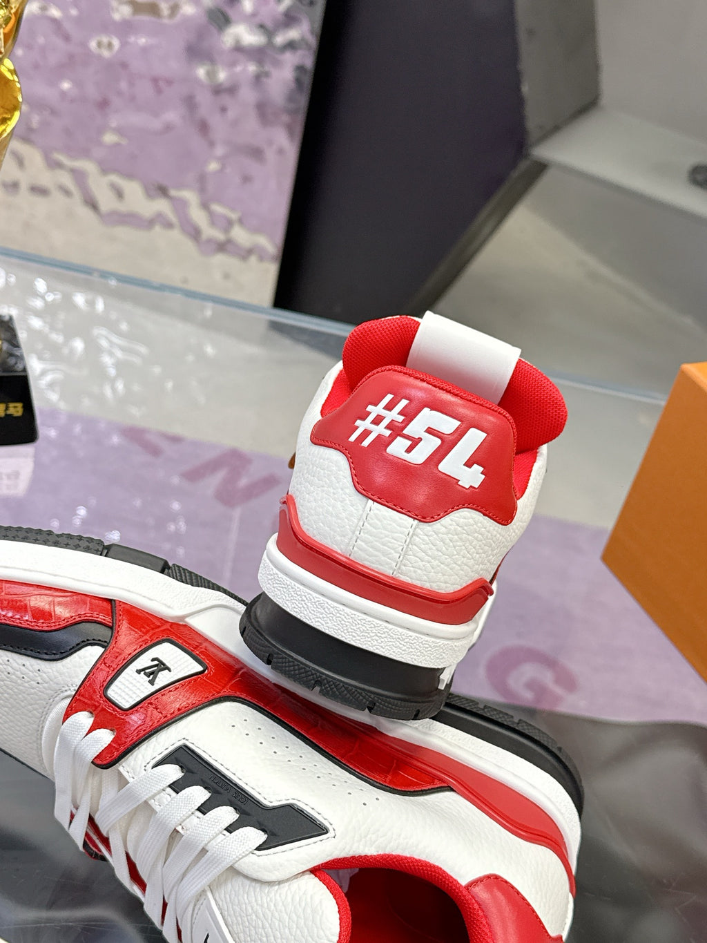 Back view of white and red Louis Vuitton sneakers with red heel tab and logo print
