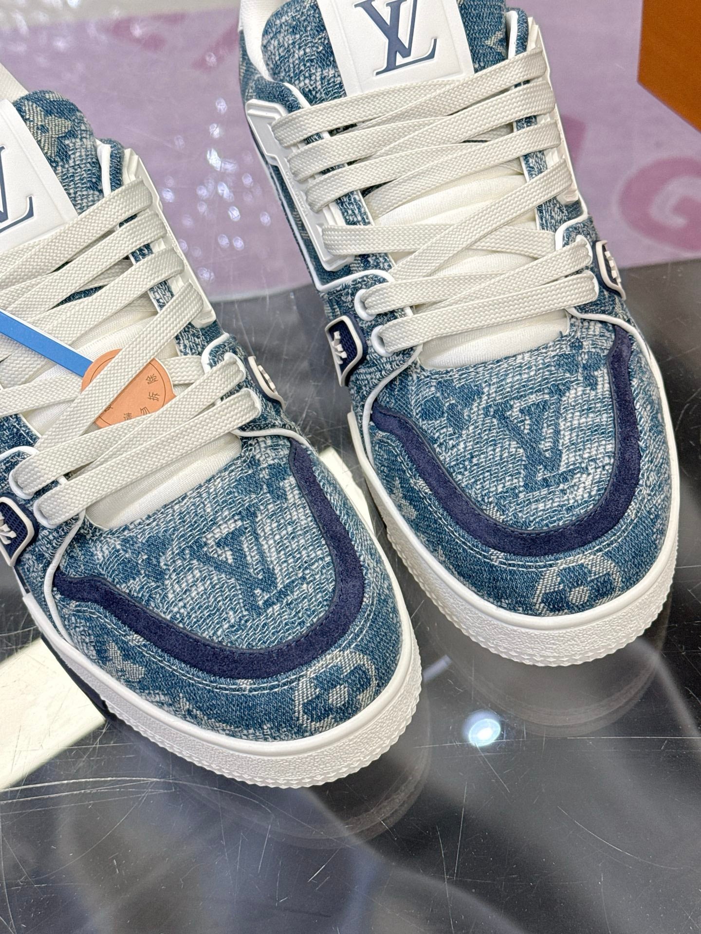 Louis Vuitton ladies sneakers close-up, blue patterned toe and side panels, white laces