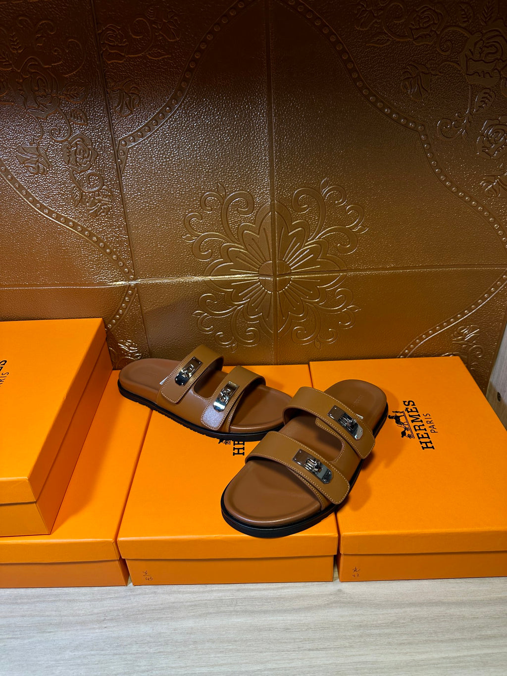 Hermes tan slide sandals with two buckled straps, angled side view