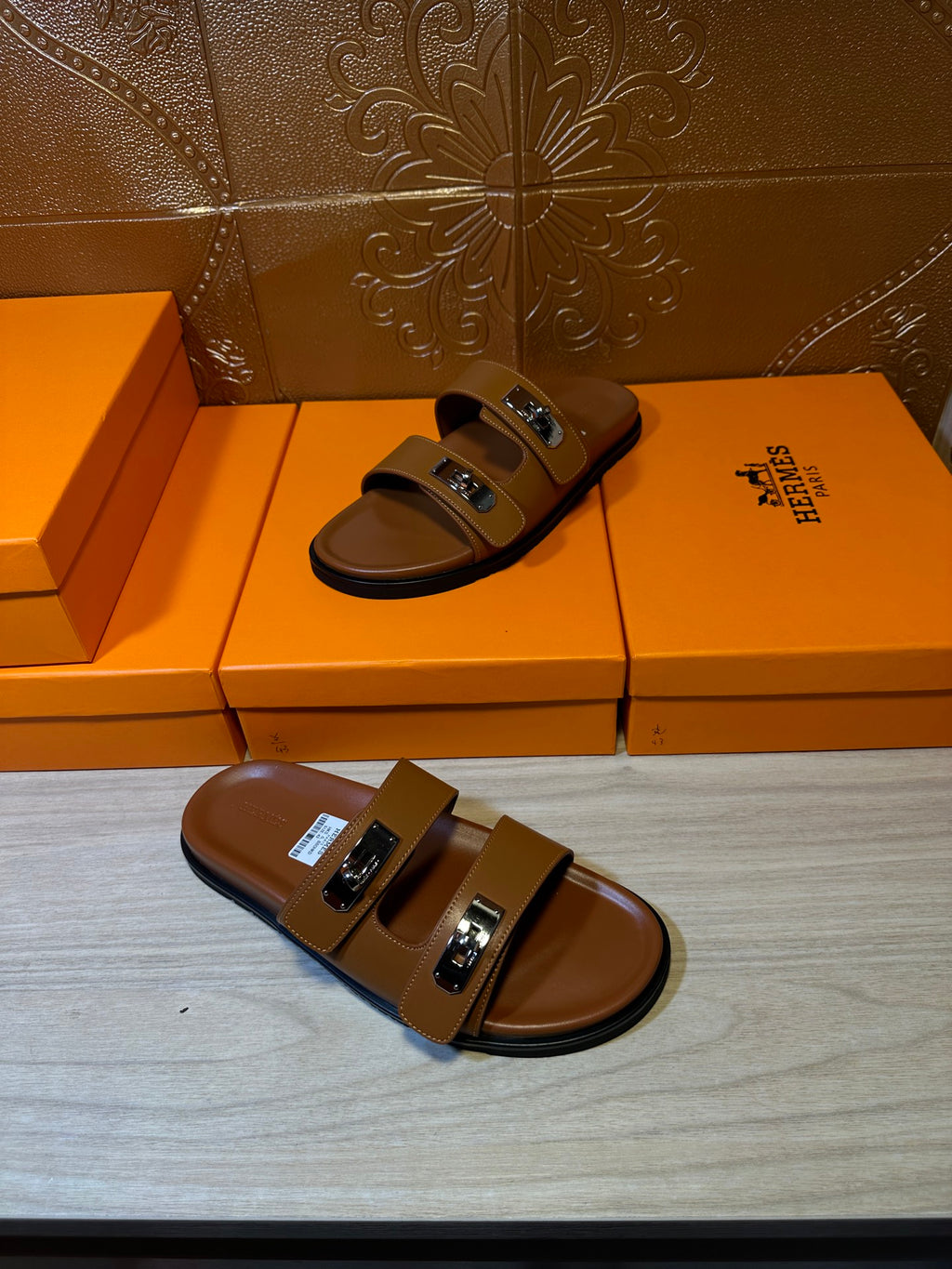 Hermes tan slide sandals with two straps and metal buckles, front view