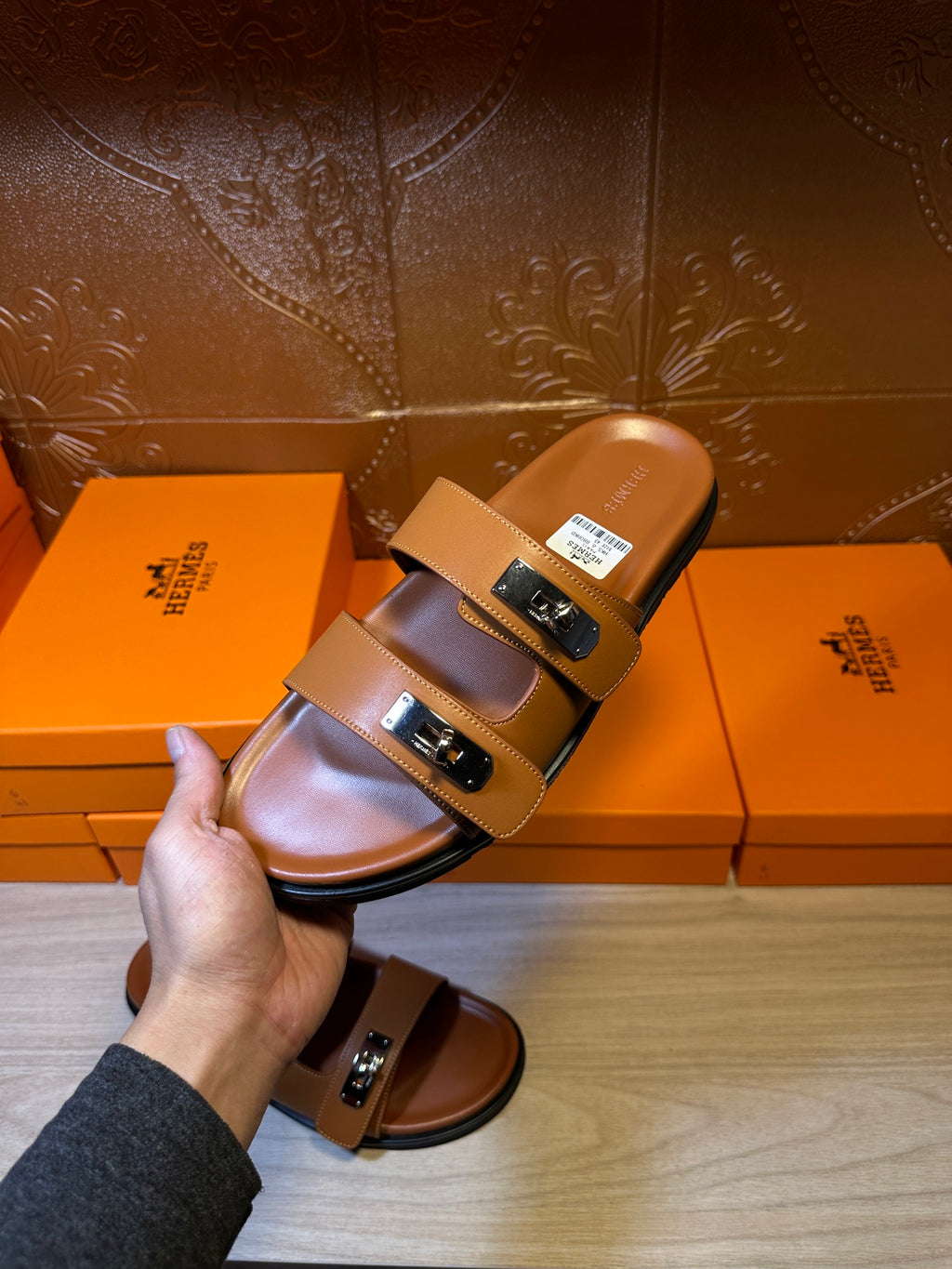 Hermes tan leather slide sandals held up, two strap buckles visible