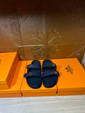 Hermes blue slide sandals with two front buckles, side-by-side on boxes