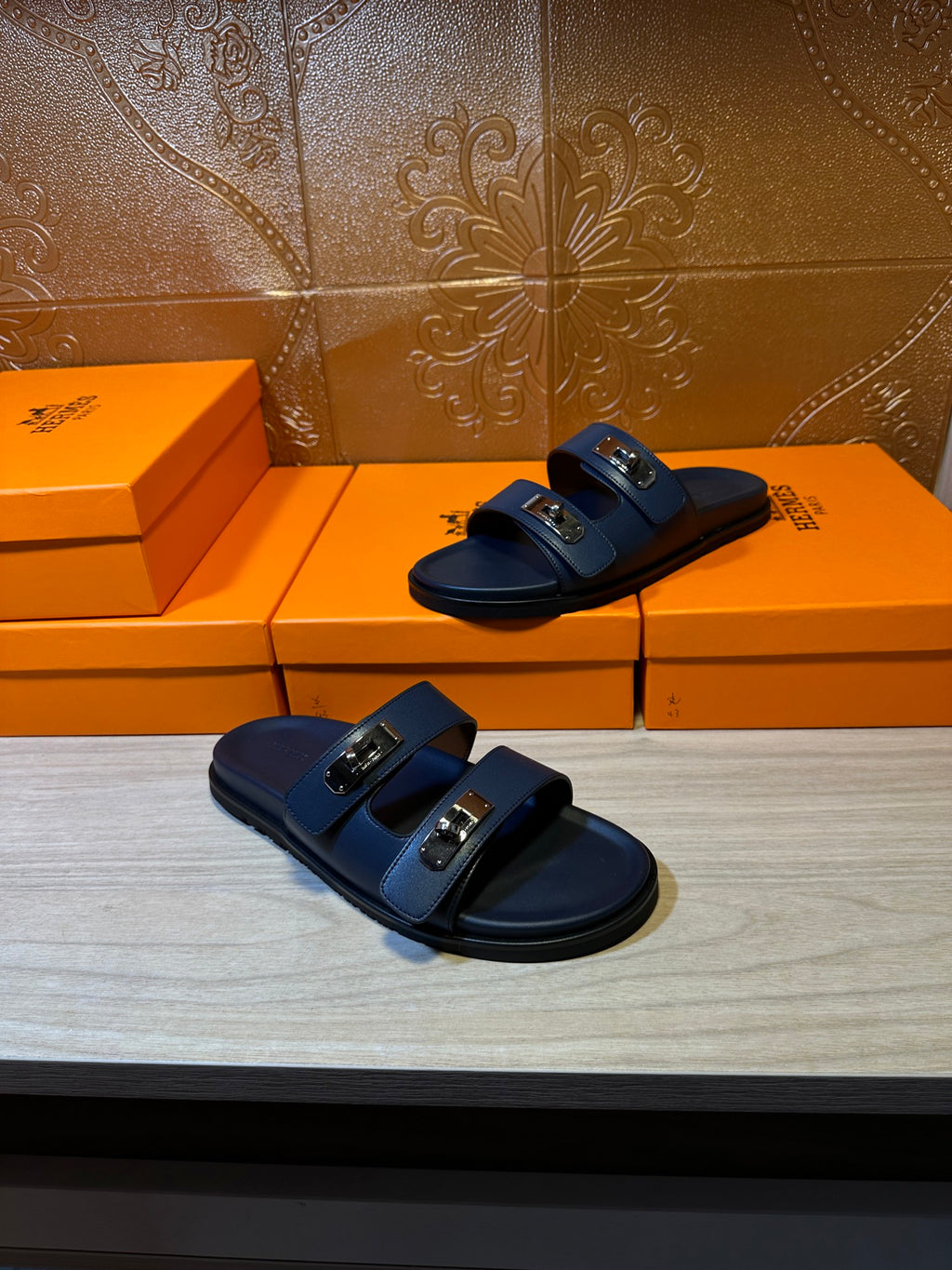 Hermes blue slide sandals with two front buckles, one pair foreground on boxes