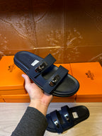 Hermes blue slide sandals with two front buckles, close-up held in hand