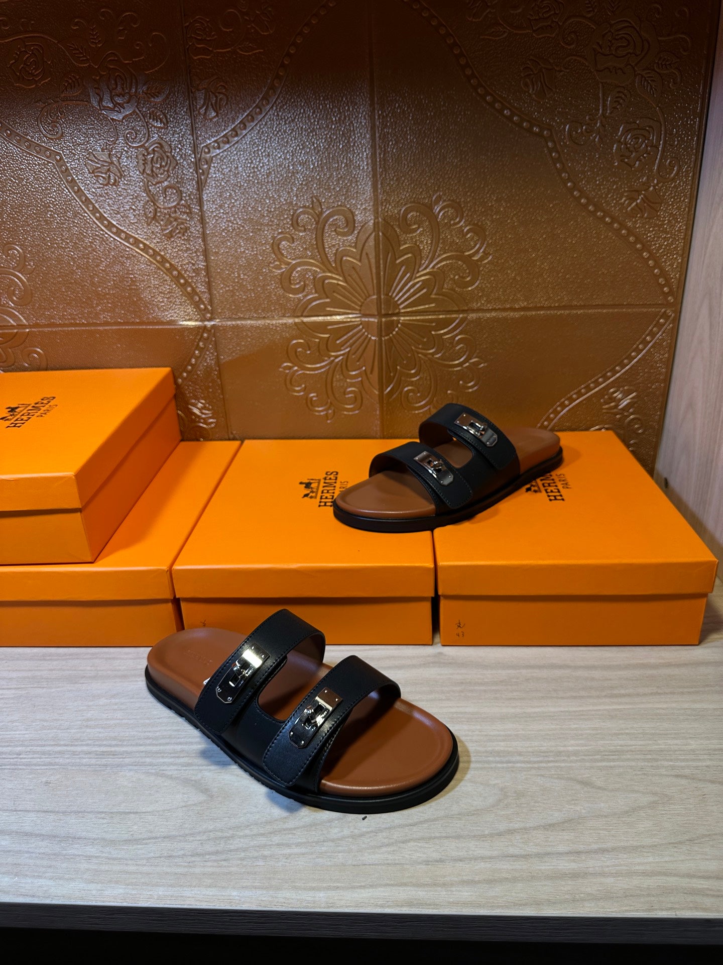 Pair of black slide sandals with two straps and silver buckles on tan soles