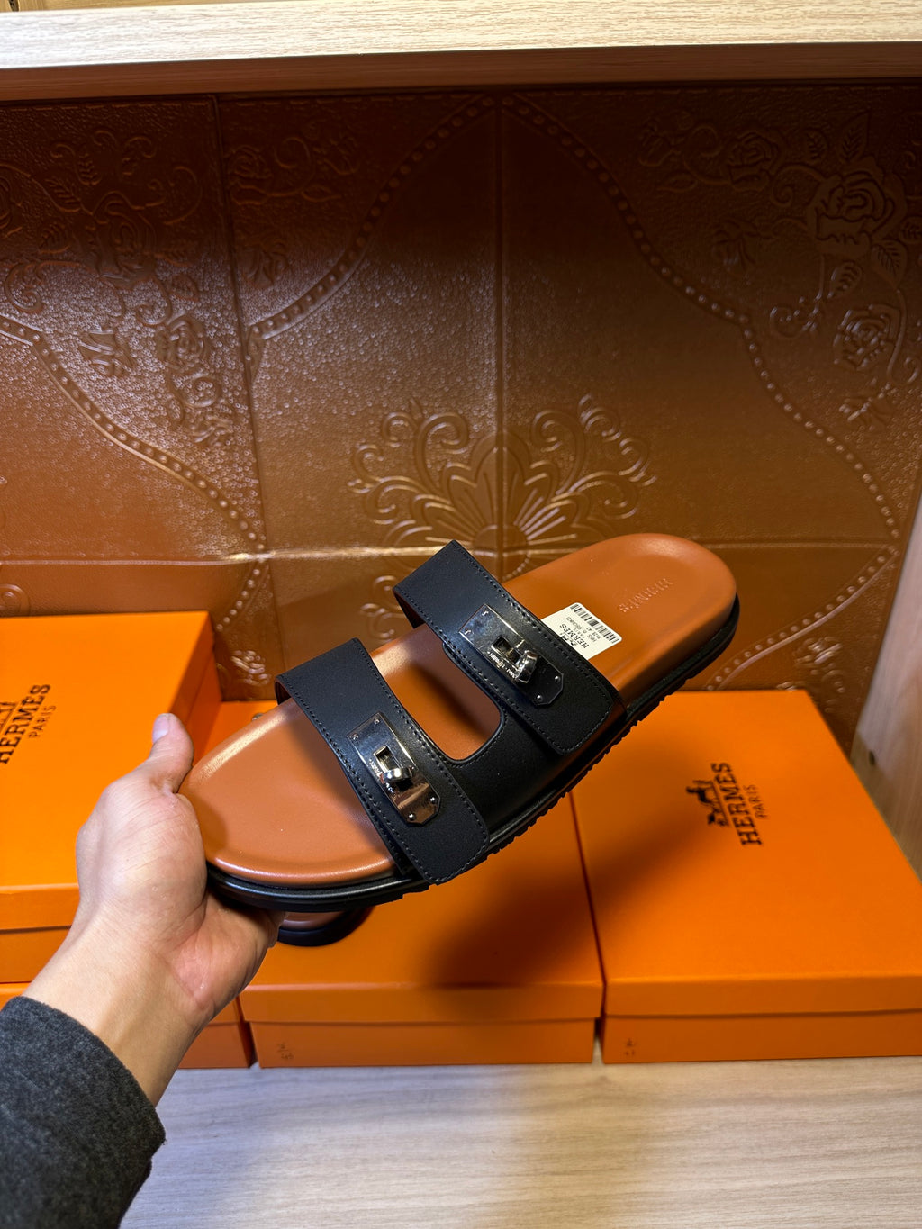 Single black two-strap slide sandal held up, showing silver buckle hardware