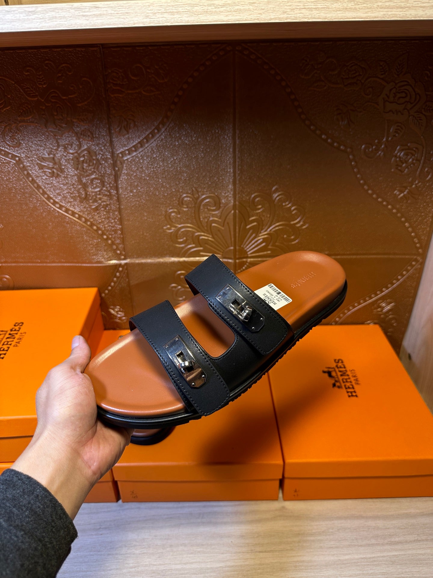 Single black two-strap slide sandal held up, showing silver buckle hardware
