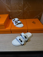 Hermes slide sandals with two white straps and metal buckles on top