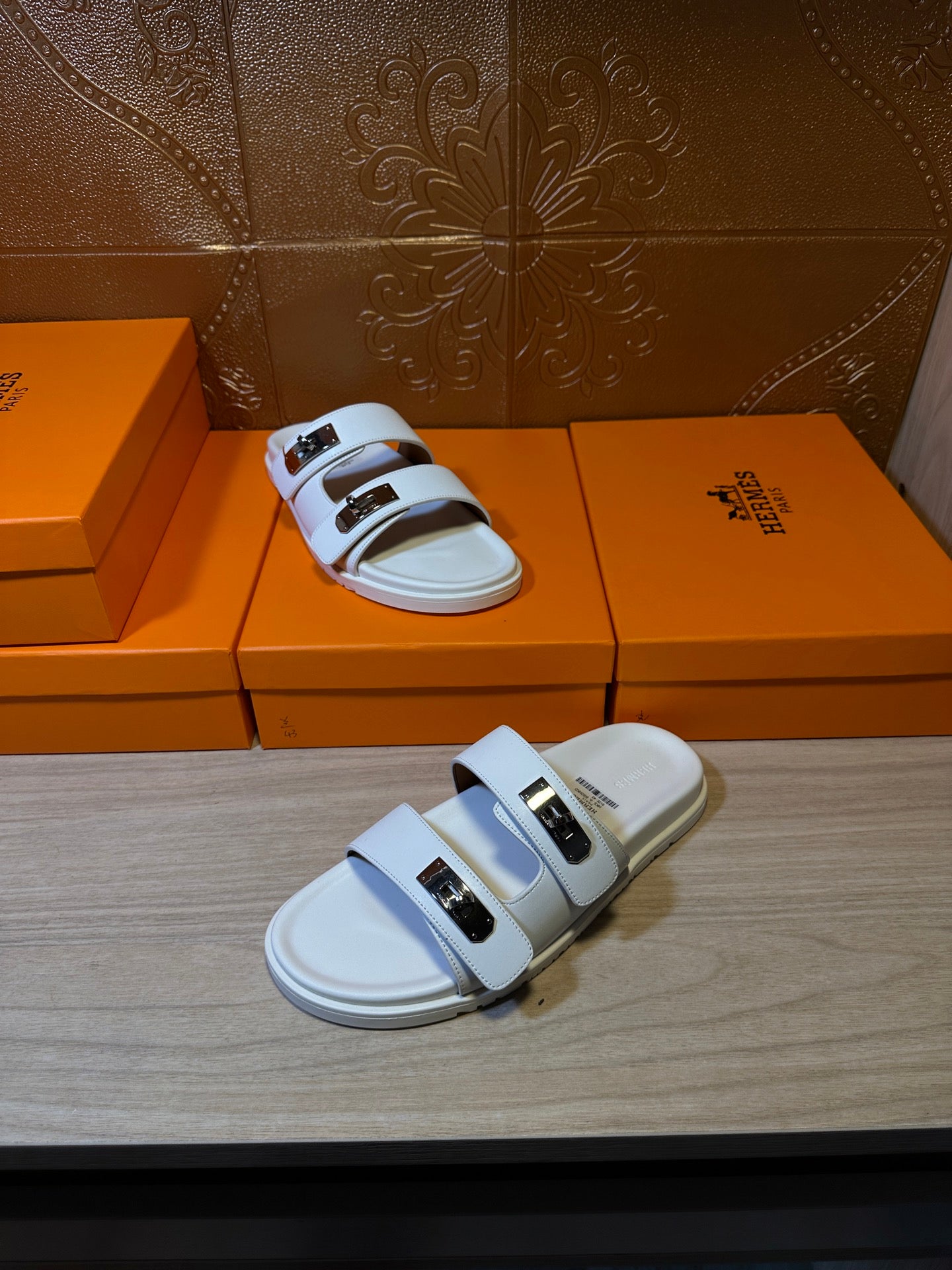 Hermes slide sandals with two white straps and metal buckles on top