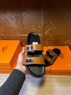 Black slide sandal with tan upper straps and silver buckle hardware in hand
