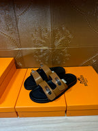 Tan and black slide sandals with dual straps and silver buckle hardware