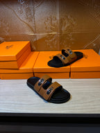 Black slide sandals with tan straps and silver buckle details on two pairs