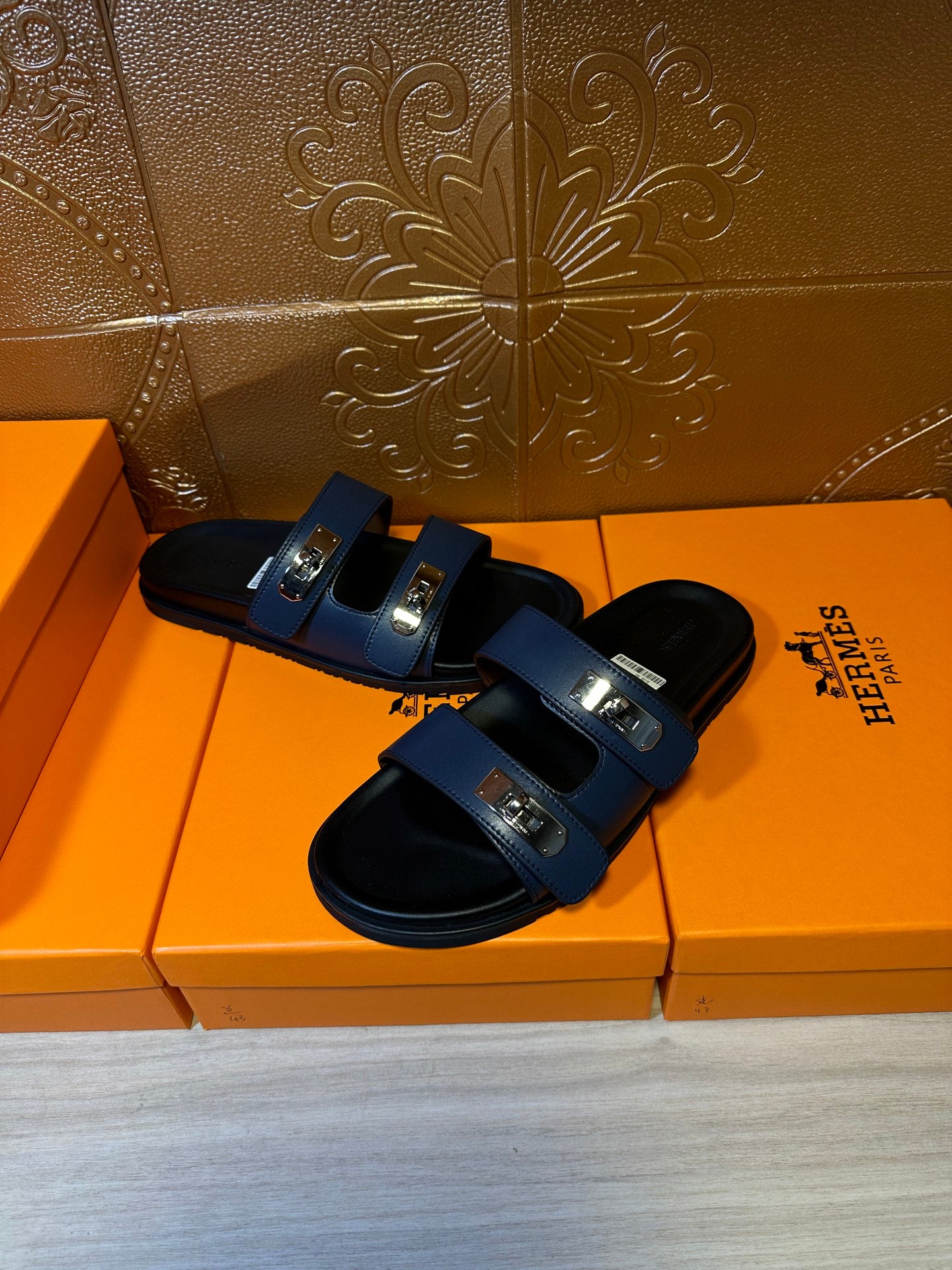 Hermes luxury sandals, navy straps across black soles with silver buckle plates.