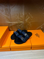 Hermes luxury sandals shown from the side, navy straps with silver buckles.