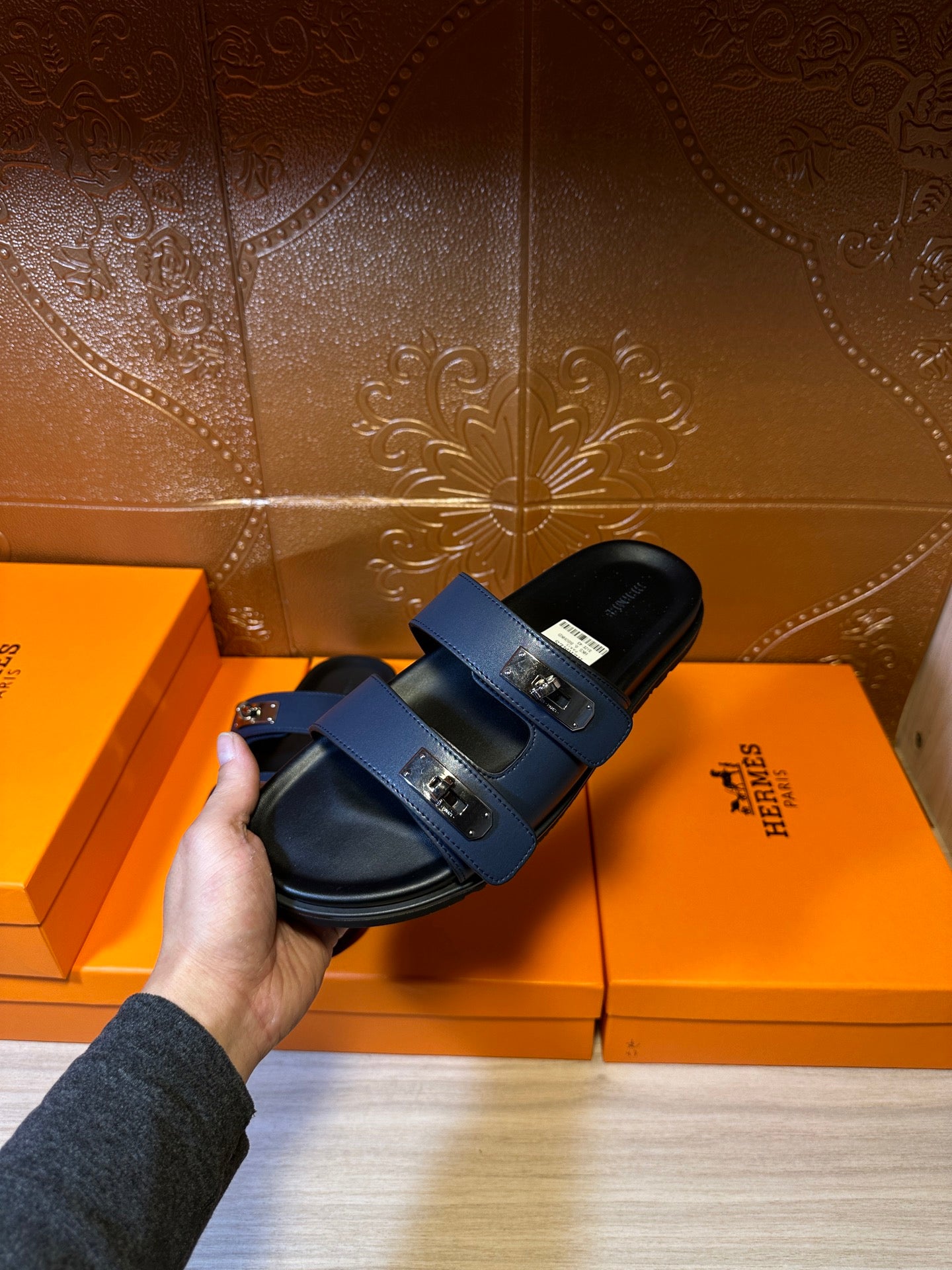 Hermes luxury sandals held up for detail, navy straps and silver buckle hardware.