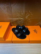 Black sandals with wide hook-and-buckle straps and flat footbed.