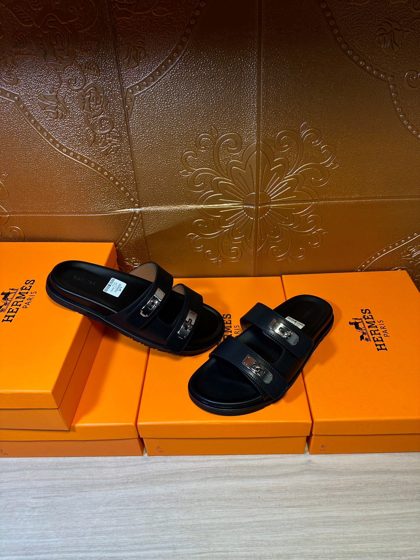 Black sandals pair with two wide straps and metal buckle hardware, flat sole.