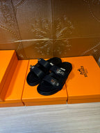 Black leather sandals with double straps and adjustable buckle, flat sole.