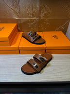 Tan slide sandals with two buckled straps, showing the open toe and footbed