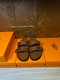 Tan leather slide sandals with double straps and silver-tone buckles, open toe