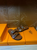 Tan slide sandals featuring two adjustable buckles on the straps