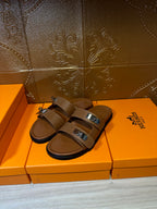 Tan slide sandals with two buckled straps and cushioned footbed on display