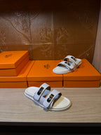 White Hermes slide sandals with two straps and silver-tone buckles, open toe