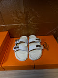 White Hermes slide sandals with two straps and silver-tone buckles, open toe
