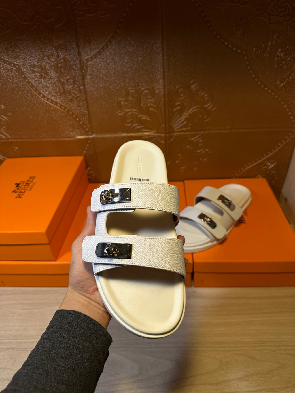 White Hermes slide sandals on hand, wide strap with silver buckle detail