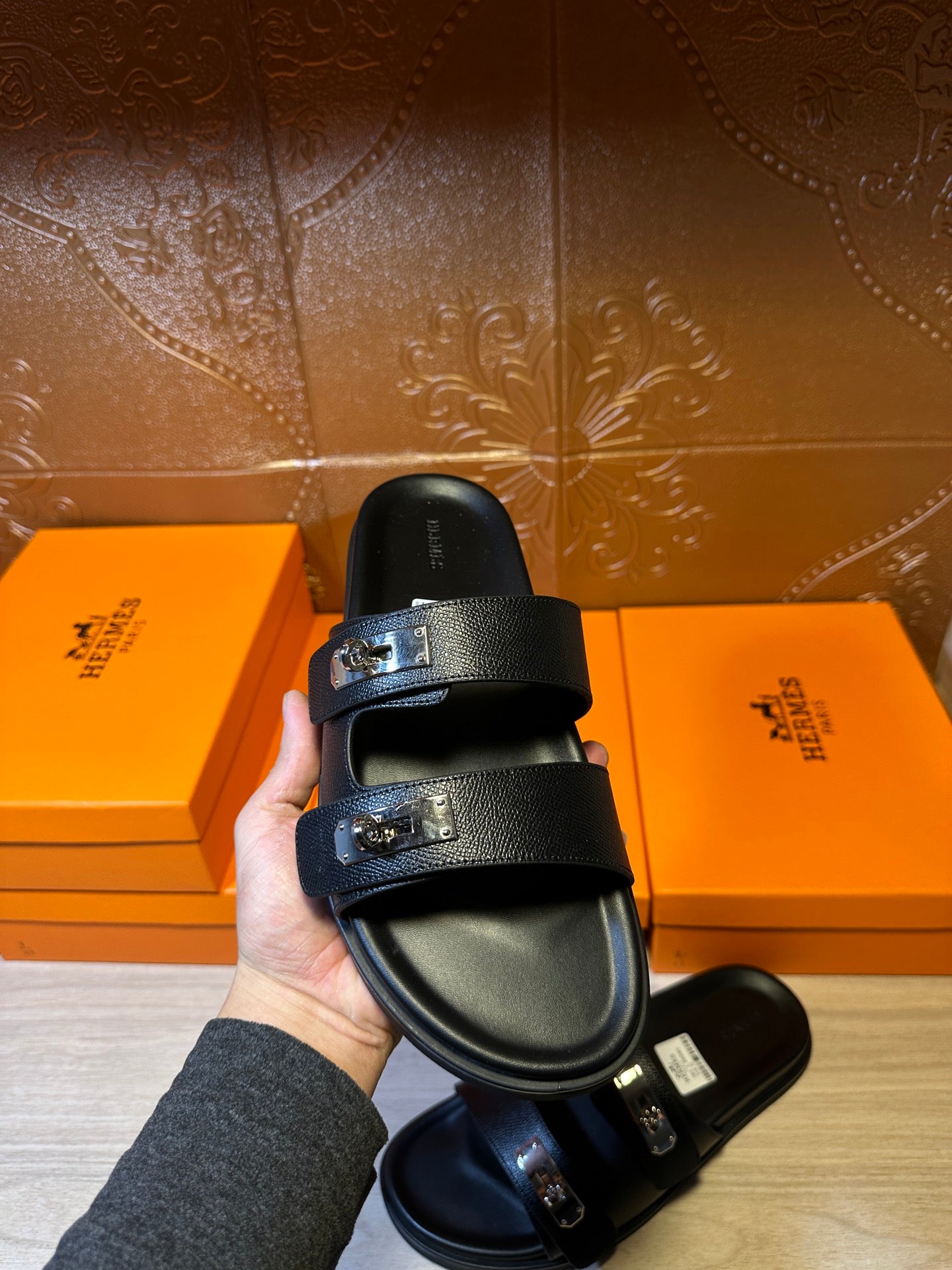 Hermes black leather slide sandals held up, two wide buckled straps