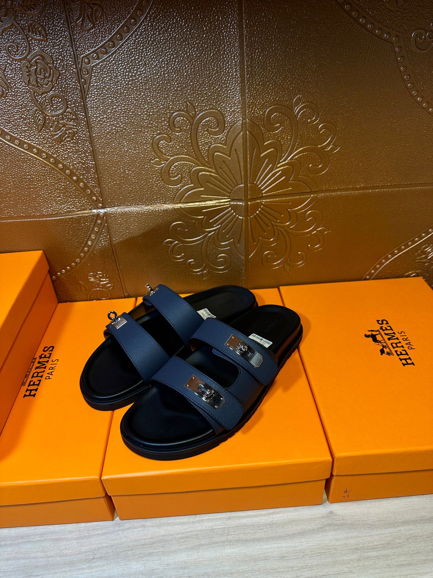 Hermes blue leather sandals on stacked orange boxes, two silver buckles