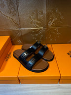 Dark leather slide sandals with double straps and embossed buckle detail