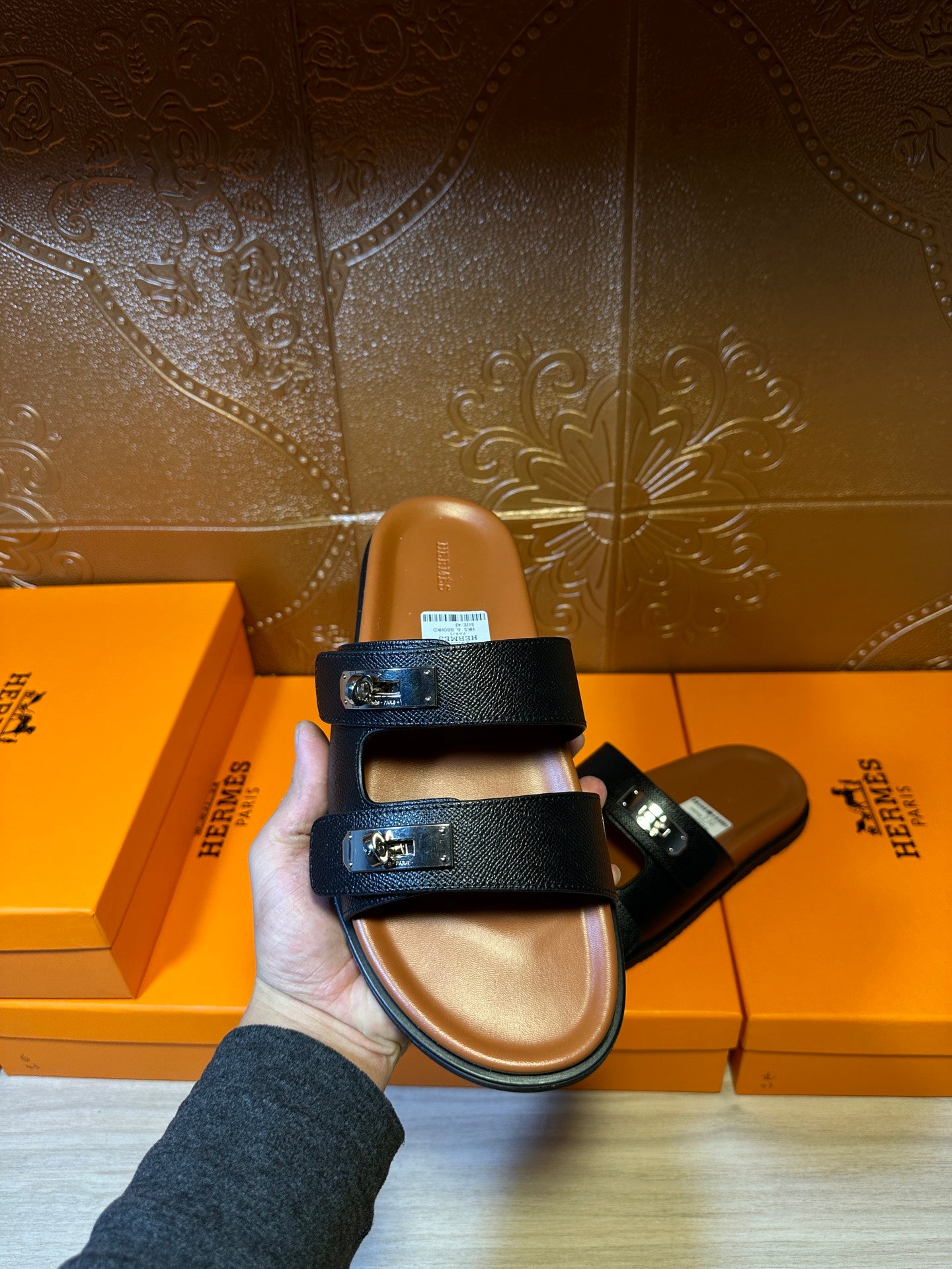 Dark slide sandals held up; double strap design with metal buckle accents