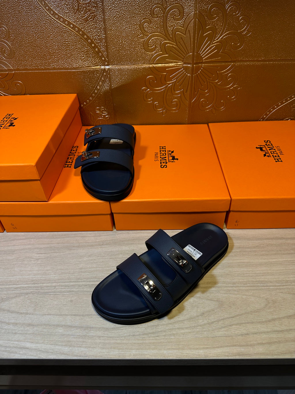 Blue leather slide sandals with two straps and metal buckles, pair on floor