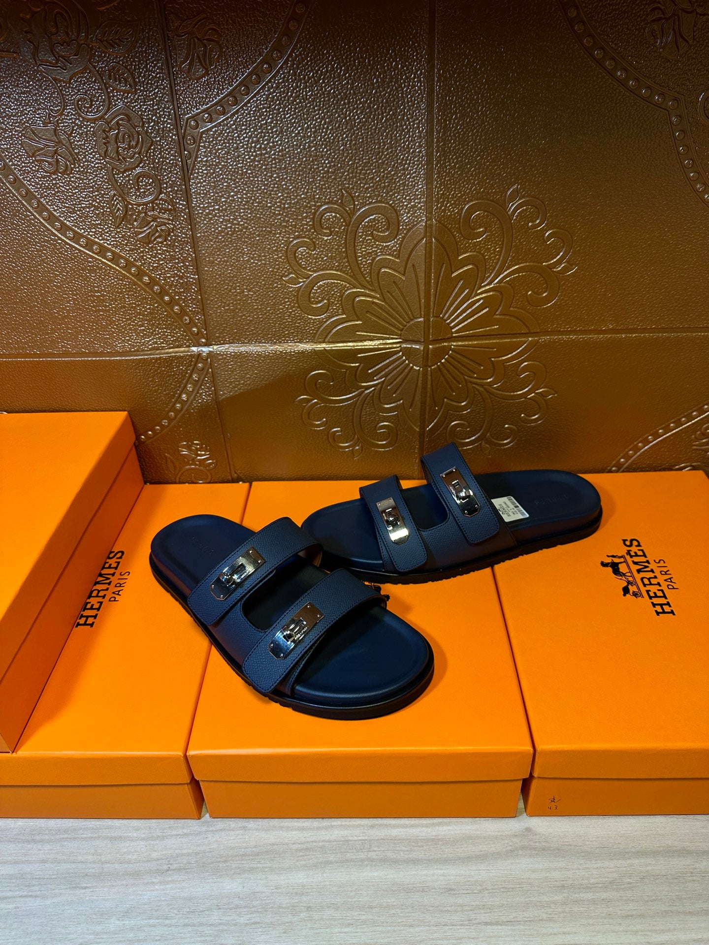 Blue leather slide sandals with two straps and metal buckles, side view