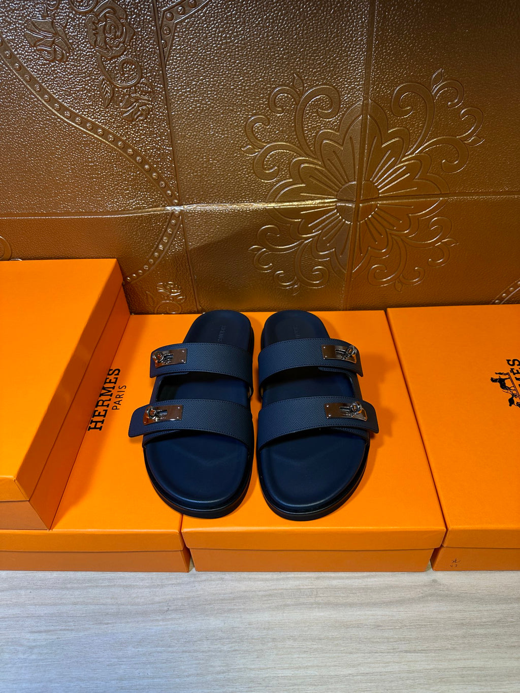 Blue leather slide sandals with two straps and metal buckles, shown from front