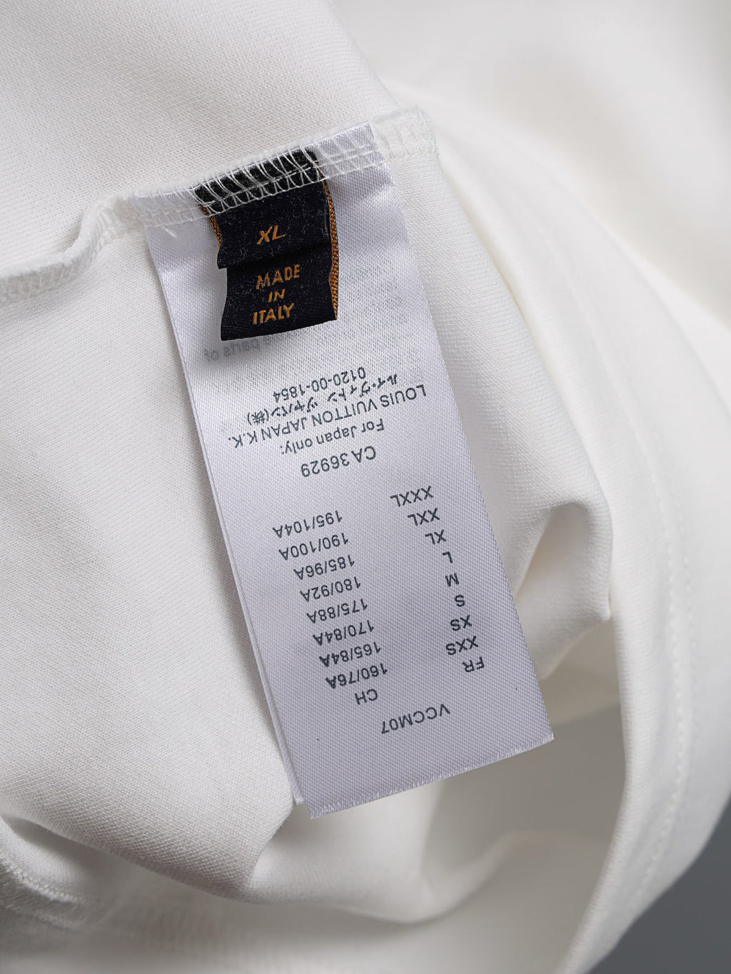 White T-shirt fabric label with size and care details, tag at inside seam
