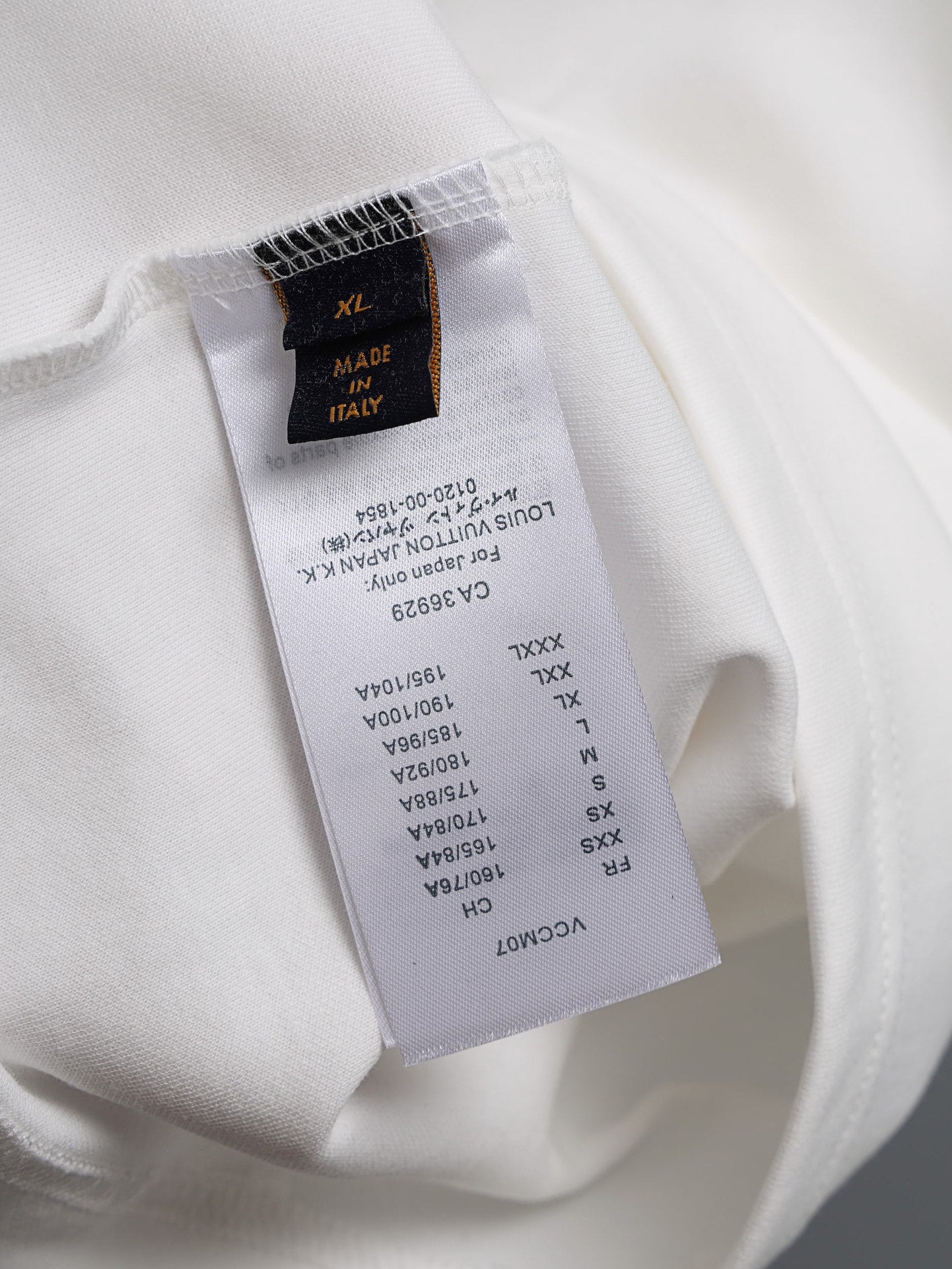 White T-shirt fabric label with size and care details, tag at inside seam