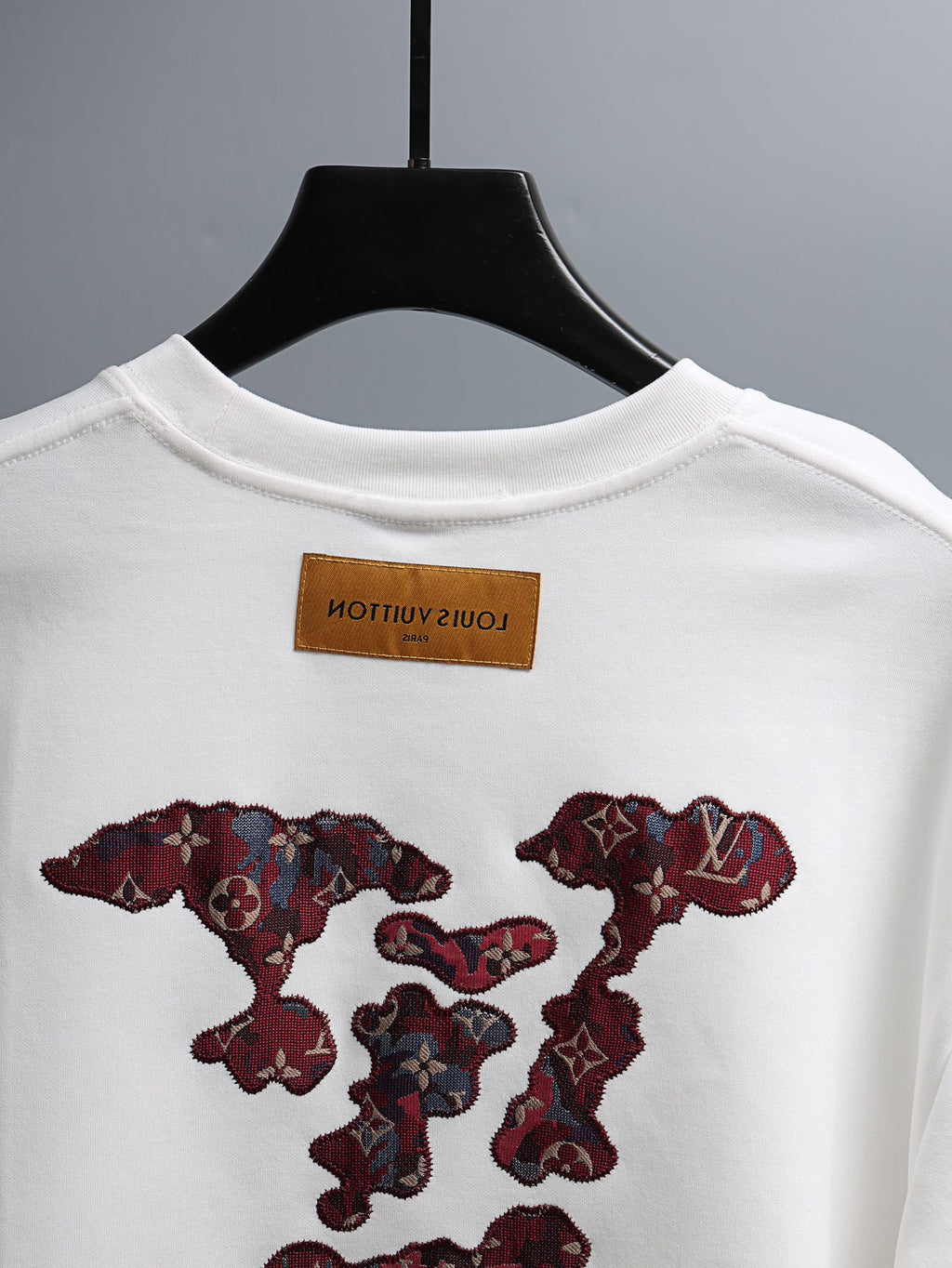 White T-shirt with round neckline, brand label, and burgundy embroidered chest motif