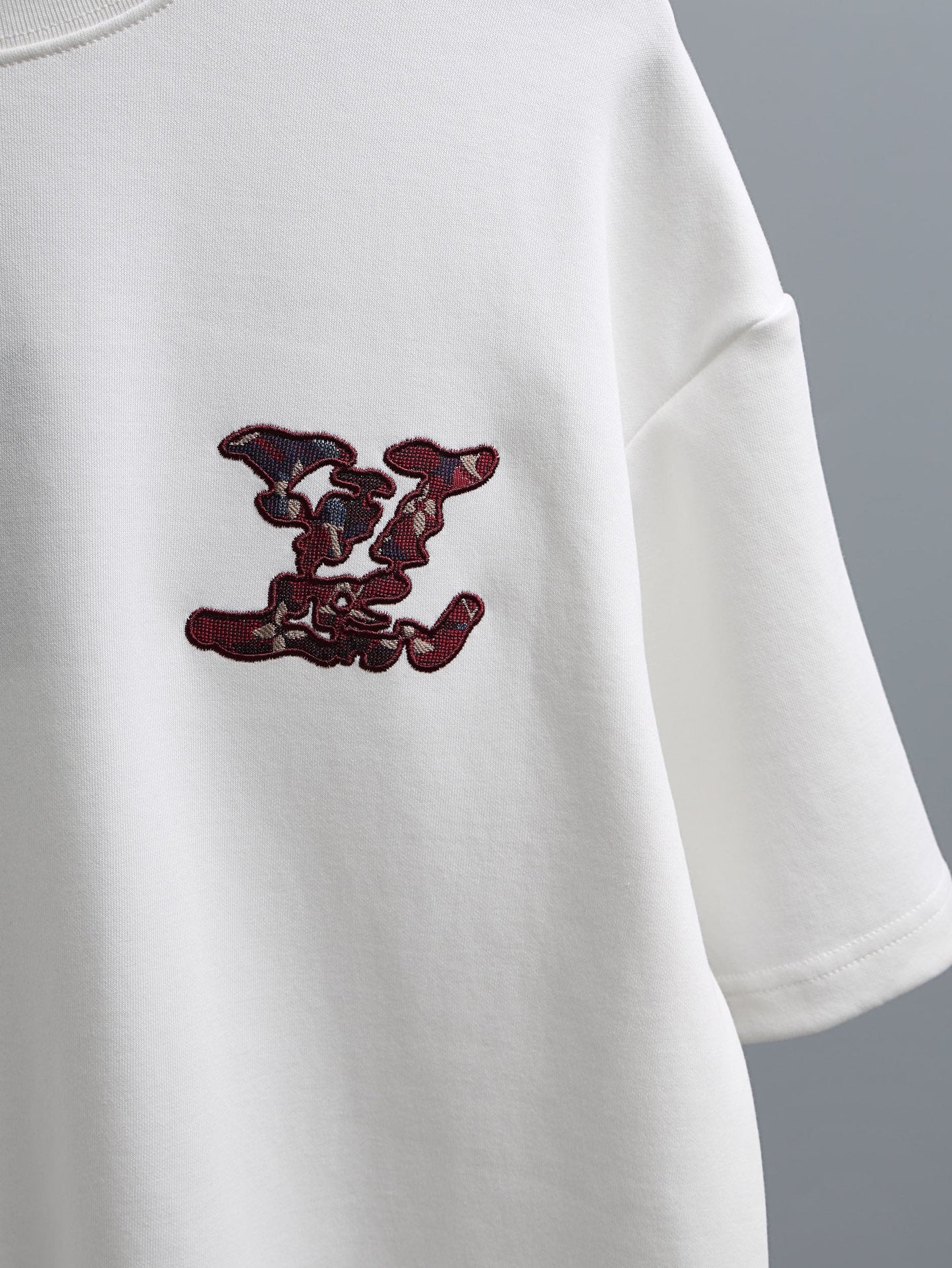 White T-shirt with burgundy embroidered logo motif on the sleeve-side chest